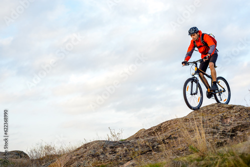 Cyclist in Red Jacket Riding the Bike Down Rocky Hill. Extreme Sport Concept. Space for Text.