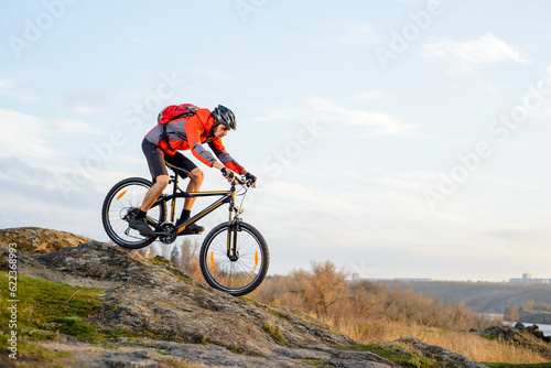 Cyclist in Red Jacket Riding the Bike Down Rocky Hill. Extreme Sport Concept. Space for Text.