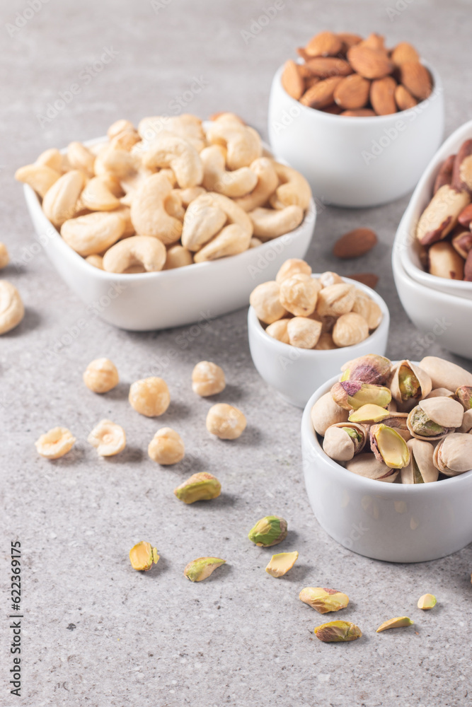 Large assortment of nuts in different bowls on stone table. Large assortment of nuts in different bowls on stone table.