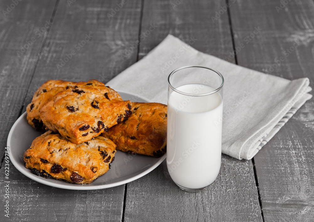 Glass of milk with fresh scones with raisins on wooden table