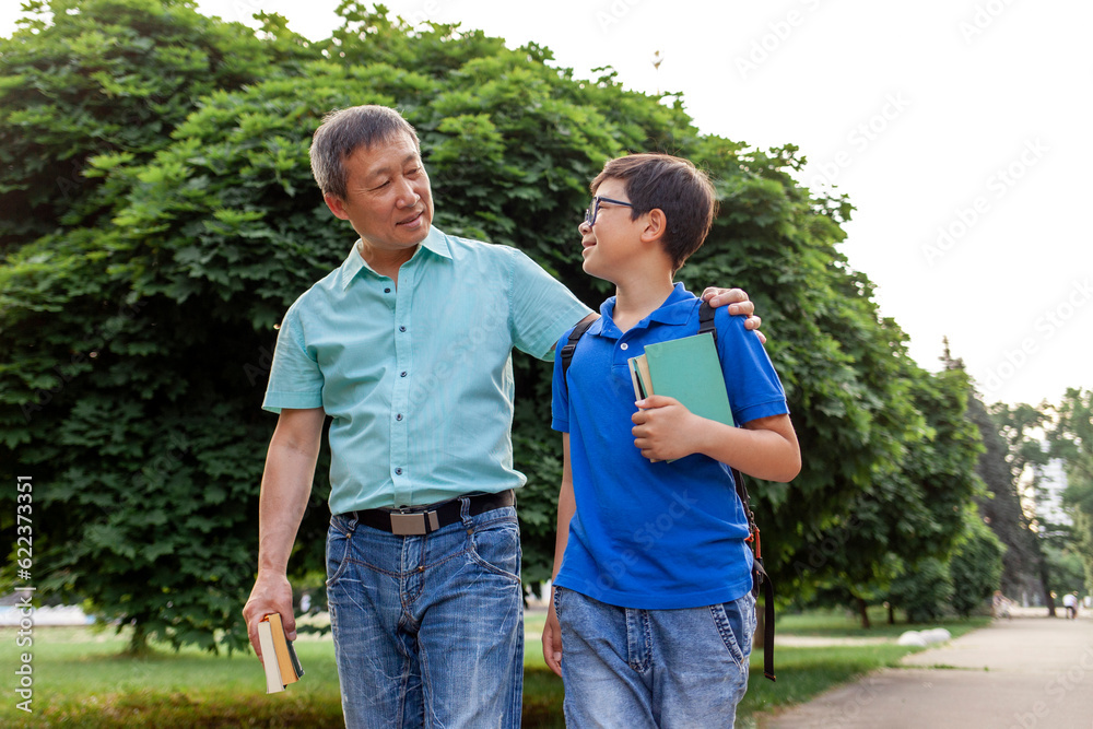 asian old father goes to school with son and carry books, korean boy with backpack and glasses goes to school asian old father goes to school with son and carry books, korean boy with backpack and glasses goes to school