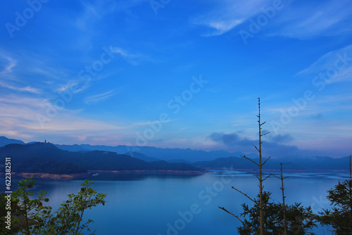 Dawn landscape with continuous mountains and colorful sky clouds and lake
