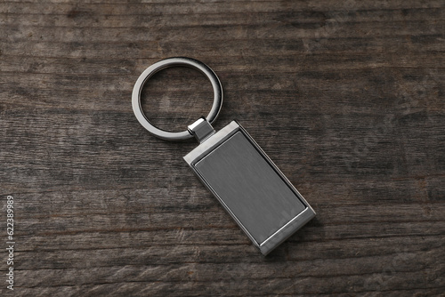 Metallic keychain on wooden background, above view