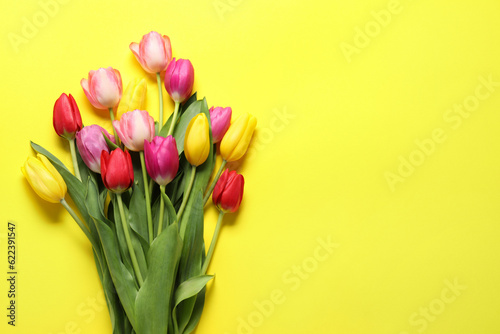 Fototapeta Naklejka Na Ścianę i Meble -  Beautiful colorful tulip flowers on yellow background, flat lay. Space for text