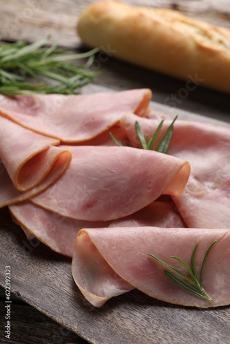 Slices of delicious ham and rosemary on table, closeup