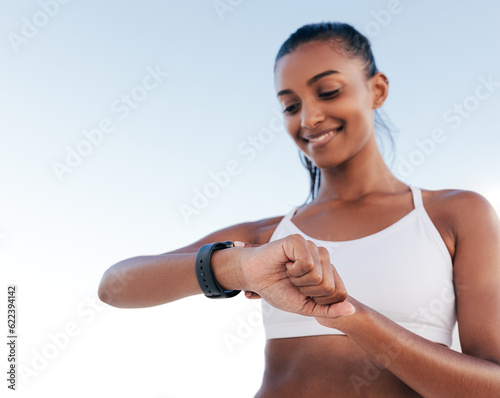 Slim cheerful female checking her pulse on smartwatch during training