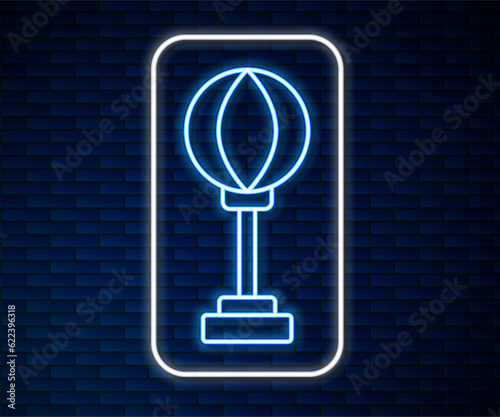 Glowing neon line Punching bag icon isolated on brick wall background. Vector
