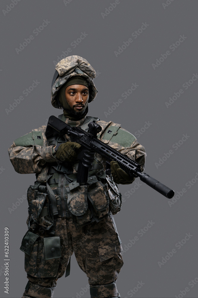 Courageous soldier in NATO uniform and helmet stands with his rifle, focused on the target, showcasing the bravery Courageous soldier in NATO uniform and helmet stands with his rifle, focused on the target, showcasing the bravery