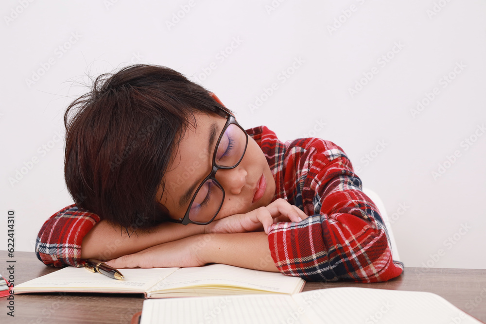 Close up photo of Tired asian student sleeping on the desk while studying. Isolated on white Close up photo of Tired asian student sleeping on the desk while studying. Isolated on white