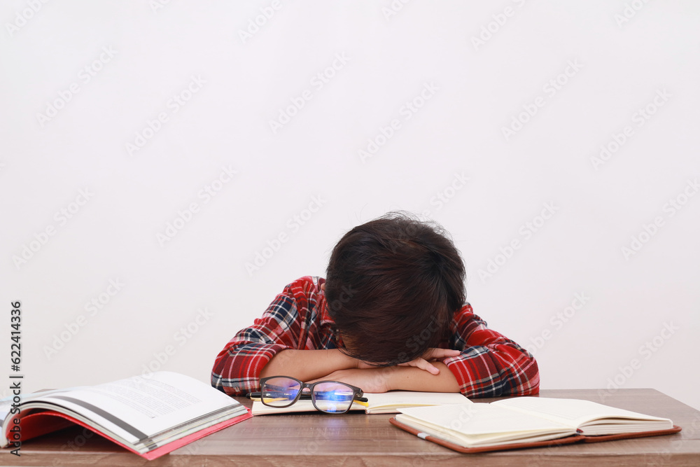Tired asian student sleeping on the desk while studying. Isolated on white background Tired asian student sleeping on the desk while studying. Isolated on white background