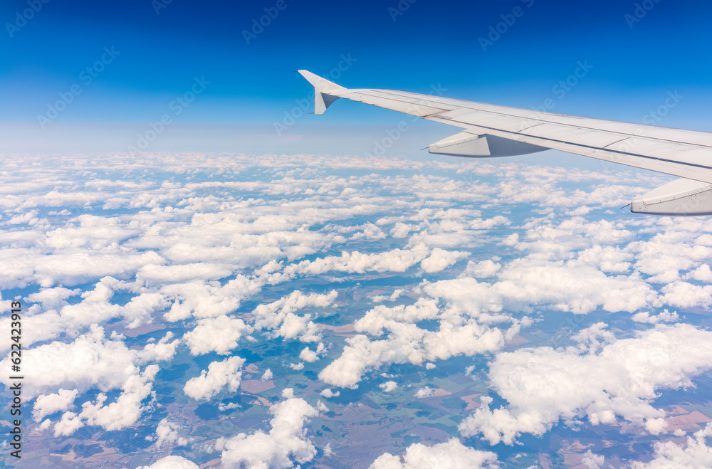 Obraz premium View from the airplane window at a beautiful cloudy sky and the airplane wing