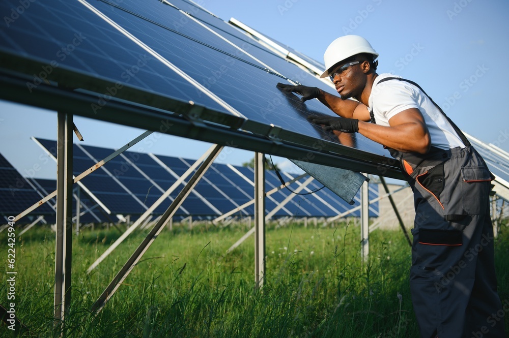 Portrait of african american electrician engineer in safety helmet and uniform installing solar panels. Portrait of african american electrician engineer in safety helmet and uniform installing solar panels.