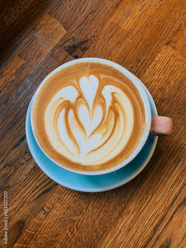 Cup of freshly made delicious cappuccino coffee with oat milk with latte art on wooden background, top view.