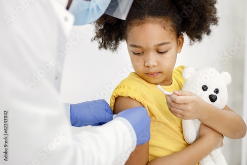 Billede på lærred Male doctor stick a band-aid on a girl's shoulder after a vaccination