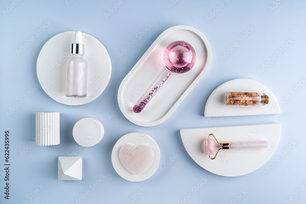 Obraz premium A face massager made of glass and roller, guasha on a white concrete podiums