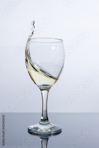 Splash of white wine in a glass on the table