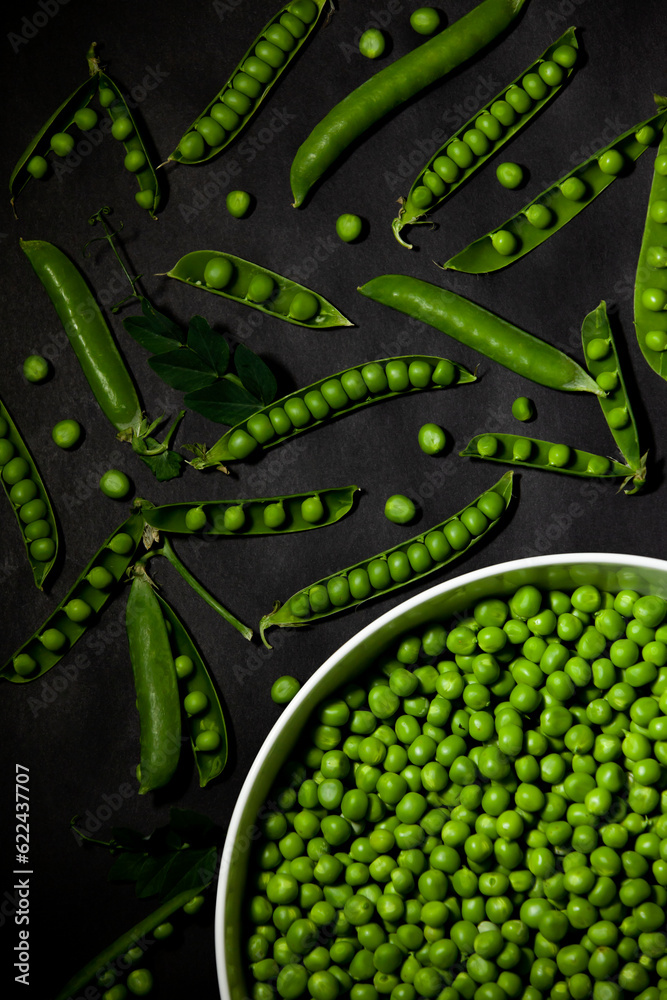 Shelled green peas in a large bowl against a dark background. Top view.