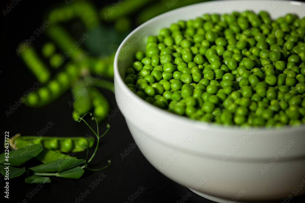 Shelled green peas in a large bowl against a dark background.