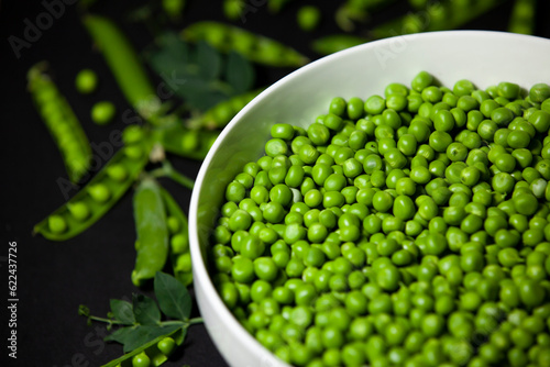 Obraz na płótnie Shelled green peas in a large bowl against a dark background. Selective focus. Top view. w salonie