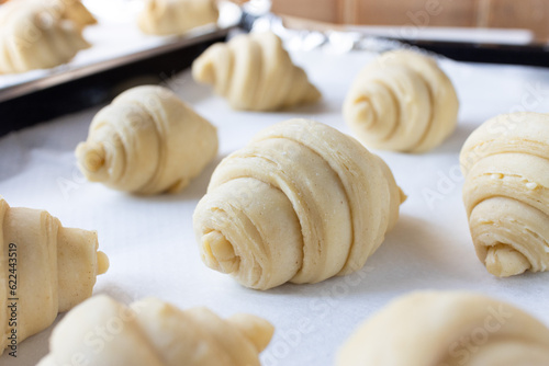 Close up of texture and layered of a fluffy leavened uncooked traditional French croissants dough roll in a baking tray. Croissant is a buttery ,flaky, viennoiserie pastry of Austrian origin