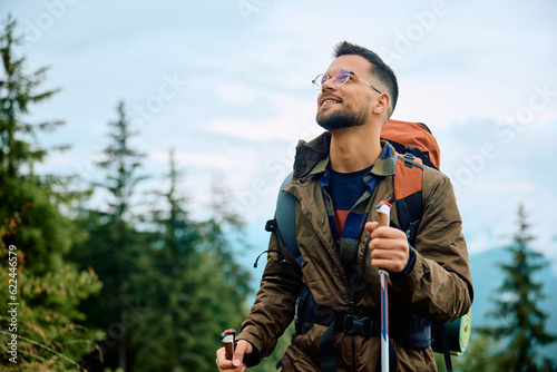 Happy backpacker using hiking pole while walking up hill. photo