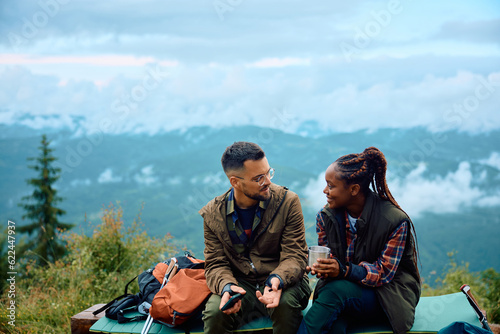 Young adventurous couple talk while relaxing father hiking in mountains.