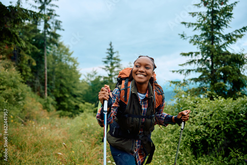 Foto Young happy African American woman hiking in nature.