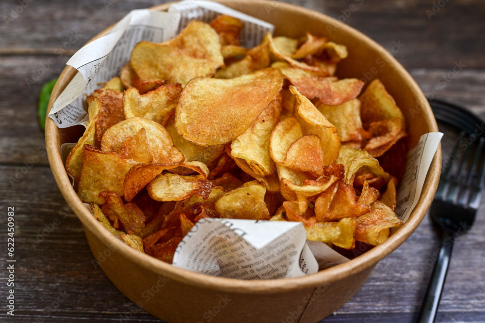 Delicious home made potato chips with sea salt and black pepper against a rustic background. Delicious snack served with sauce. Fast food.Beer snacks Delicious home made potato chips with sea salt and black pepper against a rustic background. Delicious snack served with sauce. Fast food.Beer snacks