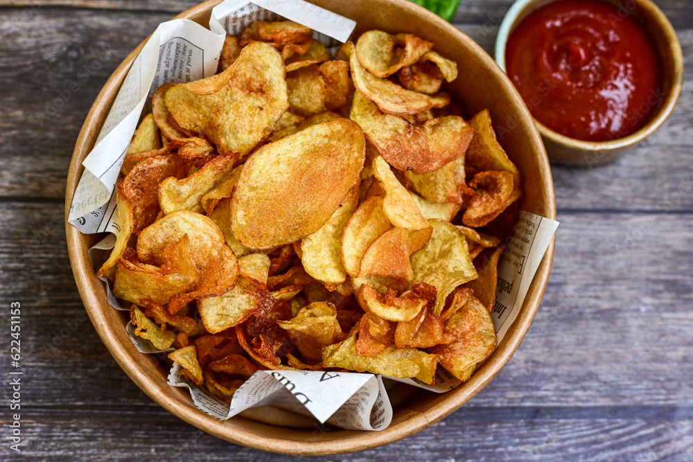 Delicious home made potato chips with sea salt and black pepper against a rustic background. Delicious snack served with sauce. Fast food.Beer snacks Delicious home made potato chips with sea salt and black pepper against a rustic background. Delicious snack served with sauce. Fast food.Beer snacks