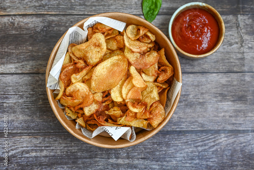 Delicious home made potato chips with sea salt and black pepper against a rustic background. Delicious snack served with sauce. Fast food.Beer snacks