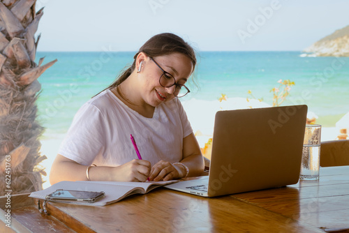 Mujer con anteojos en Teletrabajo de viaje en la playa