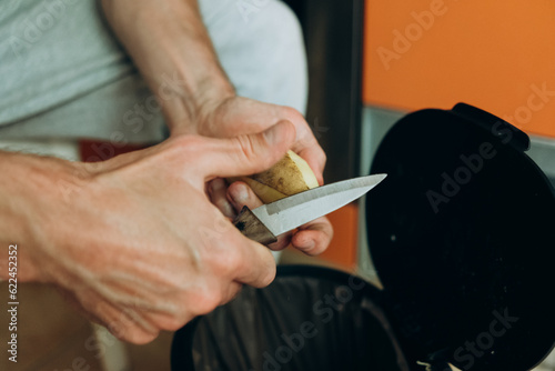 lose up on hands of unknown man peeling potatoes at home 