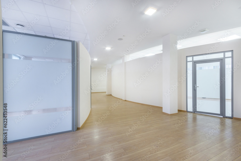 A bright corridor with curved lines in a modern office building. Brown laminate, glass .doors. A bright corridor with curved lines in a modern office building. Brown laminate, glass .doors.