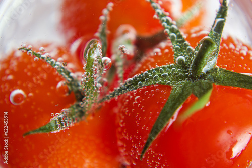 Red tomatoes in soda water with bubbles