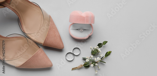 Box with wedding rings and female shoes on light background with space for text
