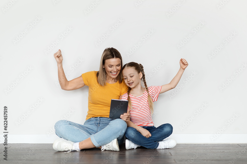 Online Win. Happy Mother And Little Daughter With Digital Tablet Celebrating Success Online Win. Happy Mother And Little Daughter With Digital Tablet Celebrating Success