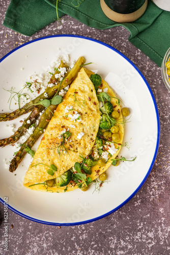 Tasty omelet with broccoli, asparagus and pea on grey background