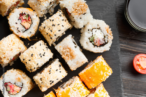 Flat lay of various sushi rolls placed on stone board.