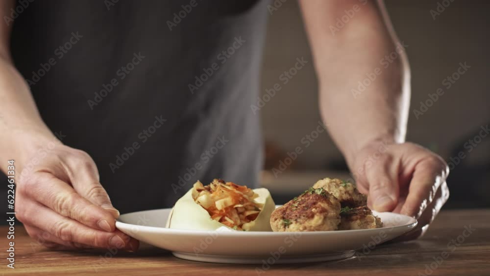 Male home chef plating a dish with Bulgarian potato patties and a cabbage and carrot salad. Male home chef plating a dish with Bulgarian potato patties and a cabbage and carrot salad.