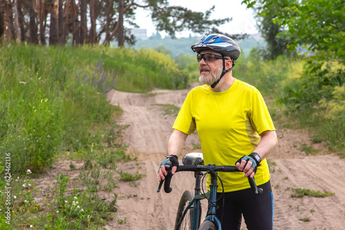 bearded man cyclist in yellow clothes rides a bike on a road in nature. sports, hobbies and entertainment for health