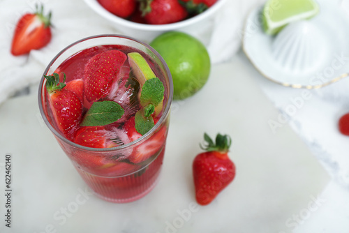 Glass of delicious strawberry mojito on light background, closeup