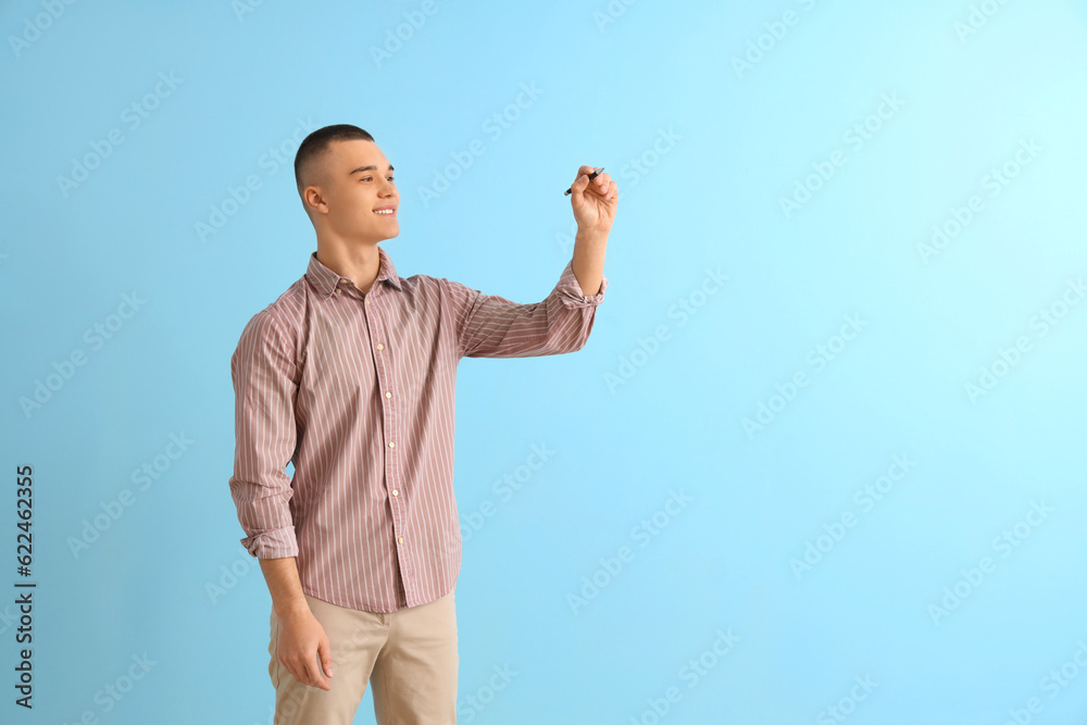 Fototapeta premium Male student with pen on blue background