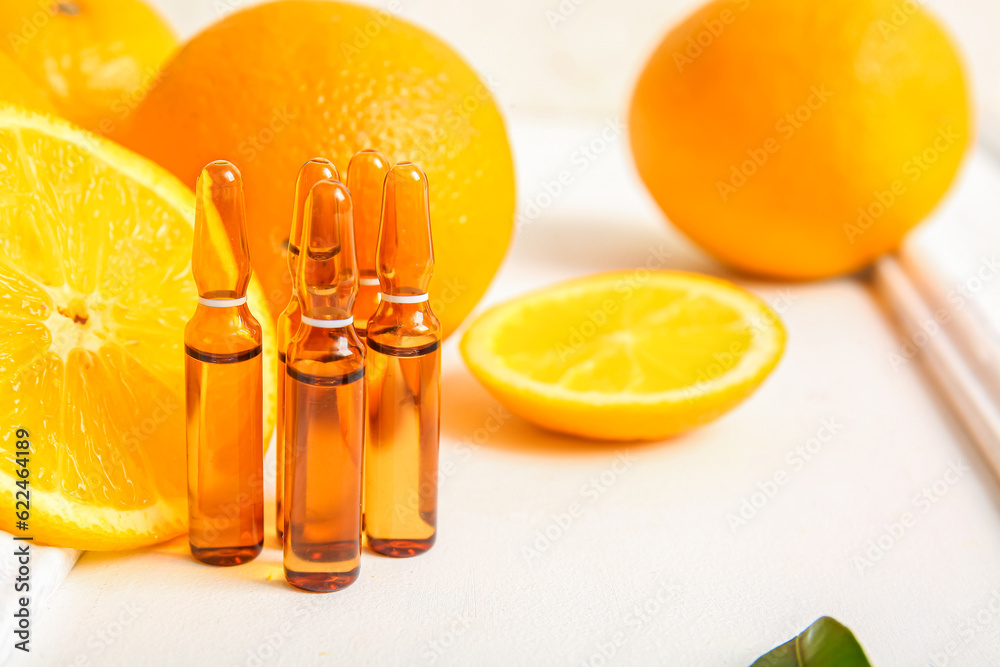 Ampoules with vitamin C and orange slices on white background Ampoules with vitamin C and orange slices on white background