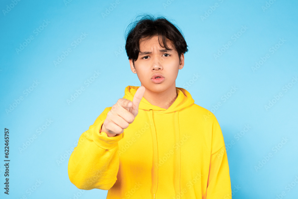 Discontented Japanese Teen Guy Pointing Finger At Camera, Blue Background Discontented Japanese Teen Guy Pointing Finger At Camera, Blue Background