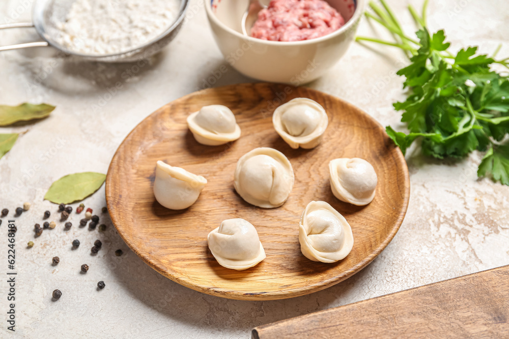 Plate with uncooked dumplings on light background Plate with uncooked dumplings on light background