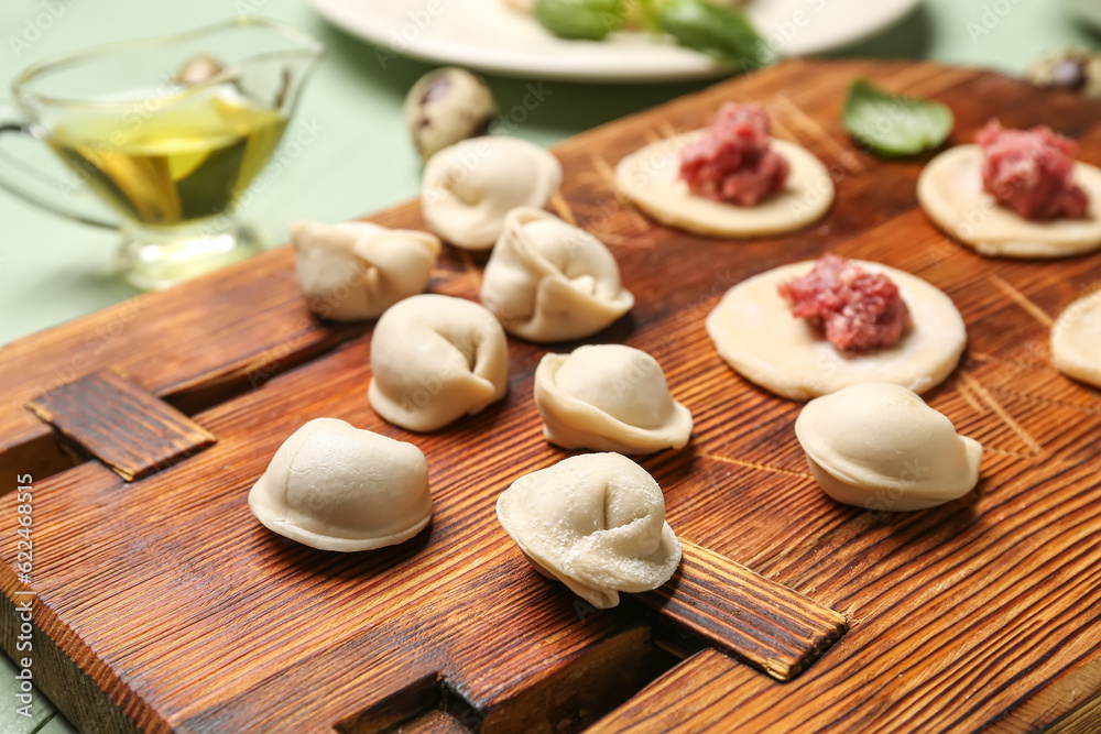 Wooden board with uncooked dumplings on table Wooden board with uncooked dumplings on table