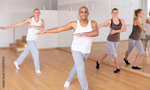 Cheerful Latino practicing vigorous lindy hop movements in group dance class