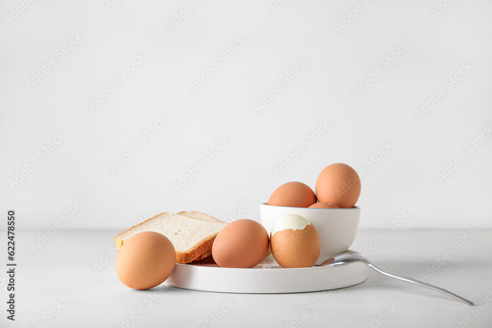 Plate and bowl with boiled chicken egg on white background Plate and bowl with boiled chicken egg on white background