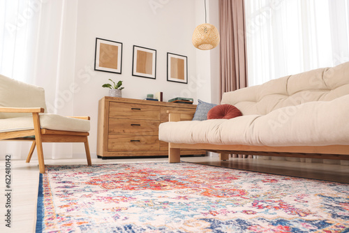 Beautiful rug, sofa, armchair and chest of drawers indoors, low angle view