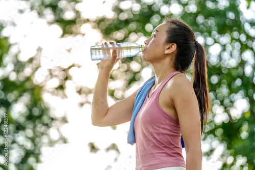 Healthy woman drinks water after workouts running exercise in the park in summer